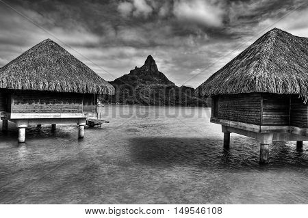 View on Mount Otemanu through lagoon and overwater bungalows on the tropical island Bora Bora honeymoon destination near Tahiti French Polynesia Pacific ocean. Black and white HDR picture.