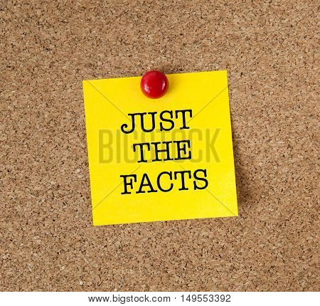 The phrase Just The Facts in red text on a yellow sticky note posted on a cork notice board as a reminder