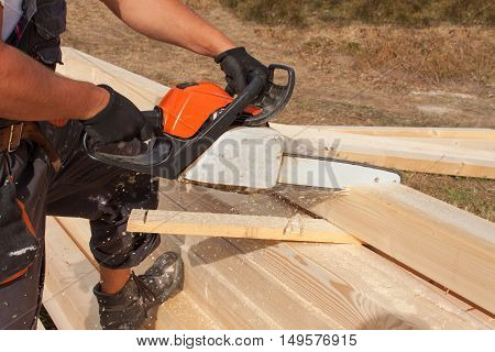 Construction Worker Cutting Beam with saw. Workers cutting timber wood with chainsaw. Saw sawing timber.