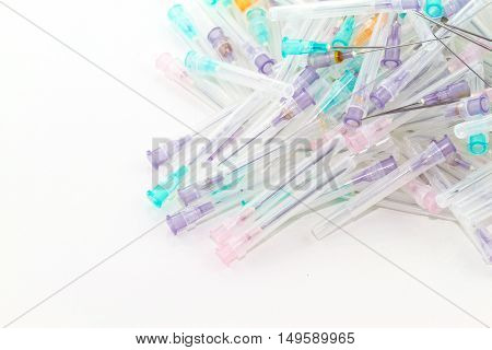 Many used syringes and needle lie strewn on white background