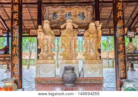 Long An, Vietnam - September 18th, 2016: Three stone statues bearing symbol 