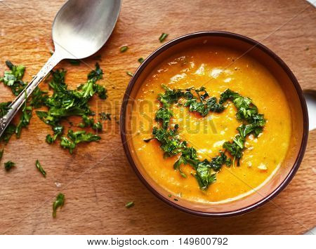 smashed pumpkin soup close up photo with parsley heart and spoon