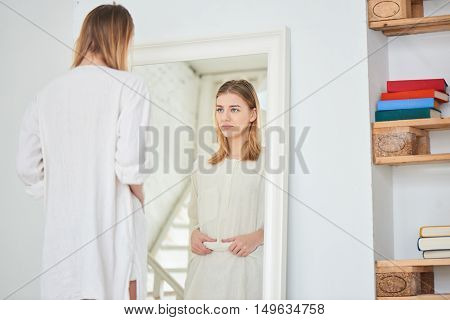 Girl unhappy with their appearance looks in the mirror