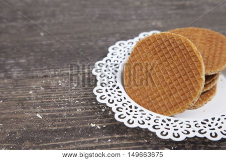 Dutch cookie stroopwafels on white plate on brown wooden background