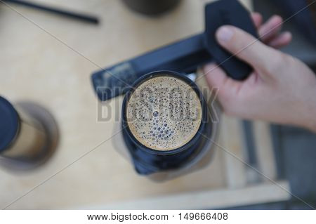 Man making fresh aeropress coffee in nature