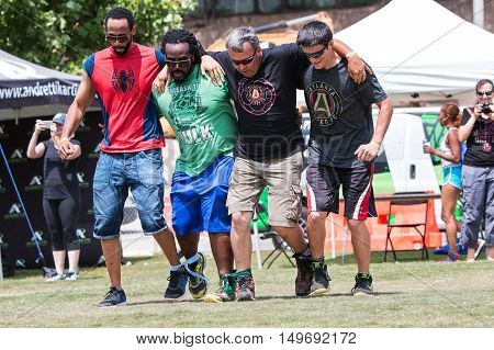 ATLANTA, GA - JULY 2016:  Men move in unison as they take part in a five-legged race one of many kid's games played by adult teams at Atlanta Field Day in the Old Fourth Ward Park in Atlanta GA on July 16 2016.