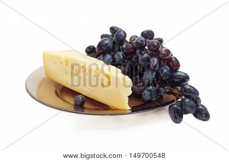 Piece of a Swiss-type cheese and cluster of a blue table grapes on a dark glass dish on a light background