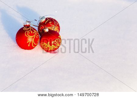 Three red christmas balls on a snow. New Year greeting card concept. Copy-space