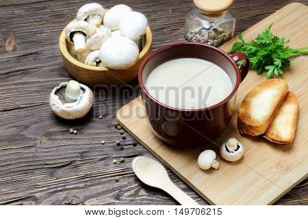 Mushroom soup puree of champignon in a brown cup on a wooden table