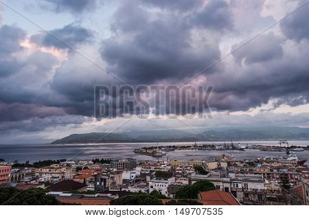 Sunset in the Port of Messina in Sicily Italy. Clouds and sunset light with night illumination.