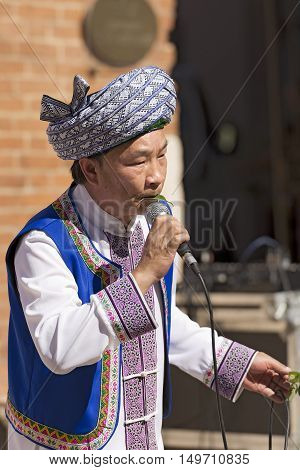VERONA ITALY - SEPTEMBER 17 2016: Tocati International festival of street games. A musician of the Guizhou province in China plays a melody by blowing air through the mouth with a leaf