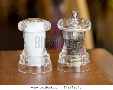 Pepper and salt in glass bottle on wood table. Ingredient for food meal.