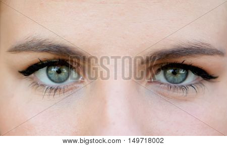 Close-up portrait of a beautiful woman with blue eyes, looking at camera