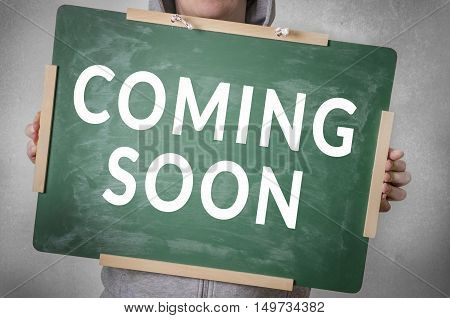 Coming soon text written on chalkboard. 
Announcement concept