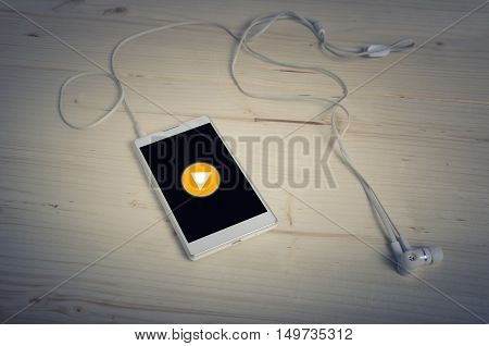 Play button on Smart phone with earphones on wooden table