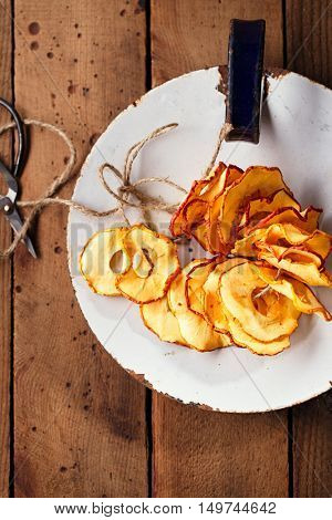 Dried apple slices on vintage enamelled dish and wooden background