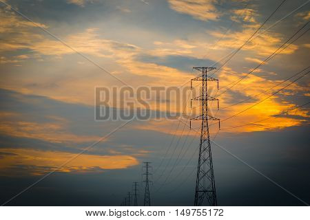 High voltage electrical transmission line and tower in rice field during sunset