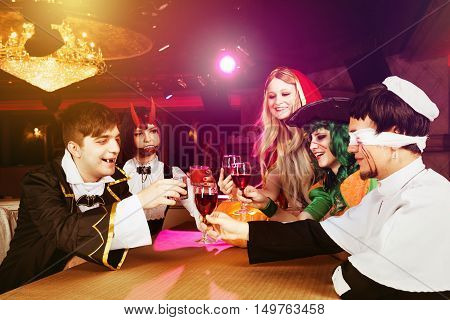 Group of friends having party in halloween costumes at night club