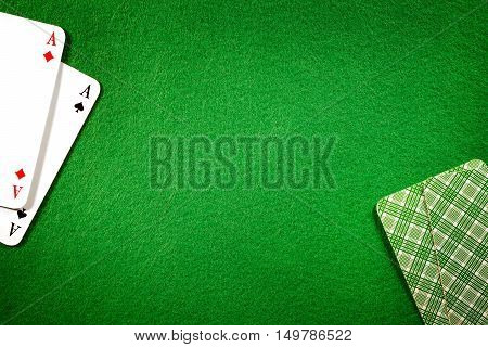 Cards on green felt casino table background. Two aces copy space in center