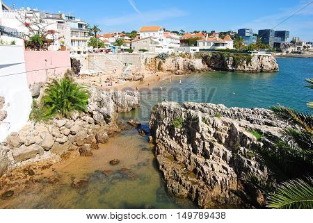 Cascais Portugal - October 23 2014. Praia da Rainha beach in Cascais with historic and commercial buildings in the distance and people.