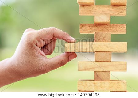 Hand Holding Blocks Wood Game (jenga) On Blurred Green Background. Risk Concept