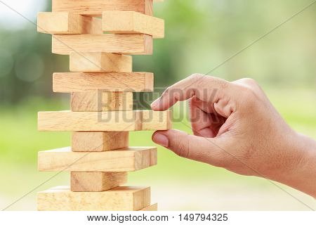 Hand Holding Blocks Wood Game (jenga) On Blurred Green Background. Risk Concept