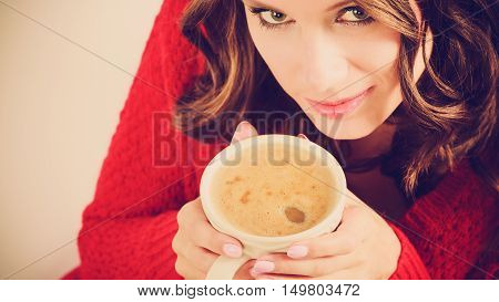 Attractive fall girl red autumnal sweater holding white mug with coffee warm beverage.Woman warming herself relaxing top view close up