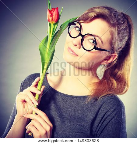 Delicacy and subtlety of women. Young adorable woman with spring flower. Portrait of beauty delicate girl in glasses with red beautiful tulip.