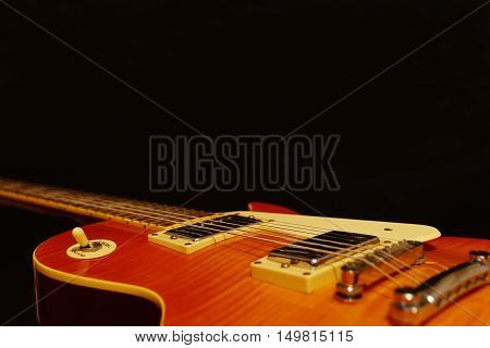 Solid body electric rock guitar closeup on the black background with plenty of copy space. Selective focus.