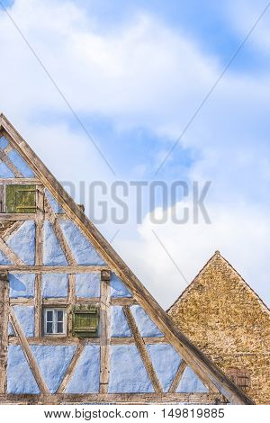 Details of medieval german gable roofs  - Medieval architecture background with two german gable roofs one house with blue half timbered walls and one with aged stone wall.