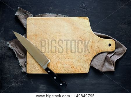 Cooking concept dark moody rustic kitchen background with an empty cutting board and Knife on it space for a text view from above