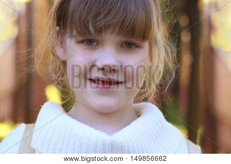 Little beautiful girl in white blouse poses outdoor at sunny summer day