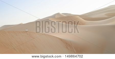 Man in traditional outfit in a desert at sunrise