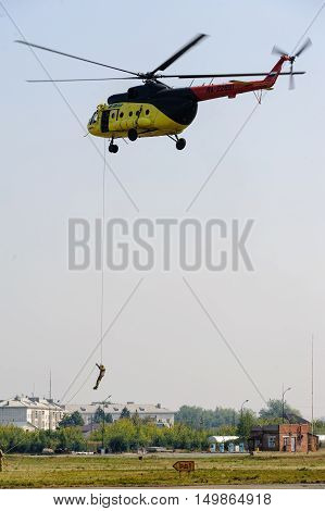 Tyumen, Russia - August 11, 2012: On a visit at UTair airshow in Plehanovo heliport. Rescuer land from MI-8 helicopter for raising of injured person