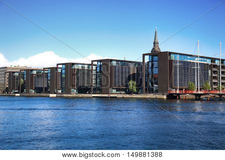 COPENHAGEN DENMARK - AUGUST 16 2016: Beautiful view on Copenhagen waterfront modern buildings and behind medieval church tower in Copenhagen Denmark on August 16 2016.