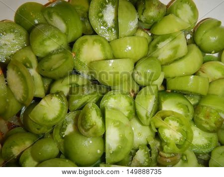 Heap of cut small green tomatoes background