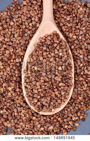 Wooden spoon with buckwheat on slate closeup