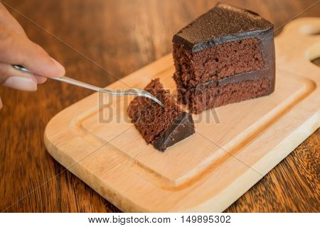 Close up Slice of chocolate cake with frok on wood table.