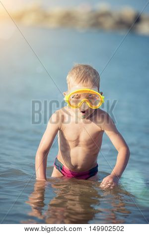 Little boy with snorkel by the sea. Cute little kid wearing mask and flippers for diving at sand tropical beach. Ocean coast.