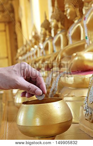 Give coin in alms bowl, a man put a Baht coin in a monk bowl for making merit or donation, buddhism Thai people donating money for temple, row of bowl