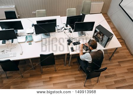 Top view on office open space with repairman. Engineer preparing workspace for work, fixing broken computer. Repair, development, business concept