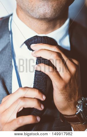 Close-up of unrecognizable man with bristle tying knit black tie