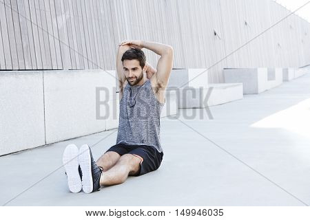 Sporty male athlete stretching in urban environment