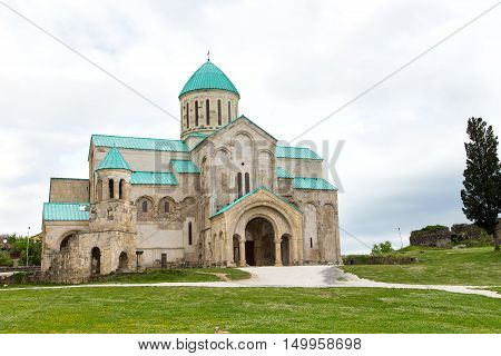 old restored temple of David the Builder Kutaisi 2014. before the temple there is a stone fence and high conifer