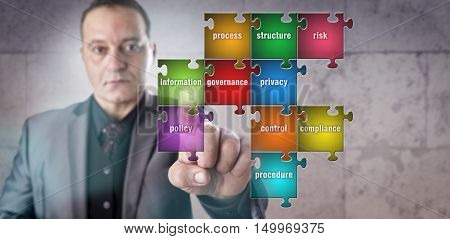 Corporate manager with determined and focused look is touching a piece in a puzzle labeled information. Data management metaphor for information governance compliance and operational transparency.