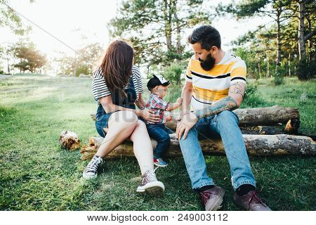 Dark-haired Hipster Family In Nature, Bearded Dad With Tattoos And Stylish Clothes.