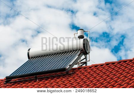 Solar Water Heater Boiler On Residentual House Rooftop, Blue Sky With White Sky Background.