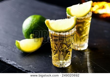Gold Mexican Tequila With Lime And Salt On Dark Table
