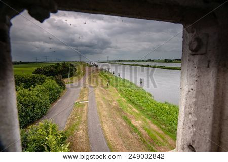 Landscape With The Water Of The Ijssel Delta And Threatening Rain Showers Over Green Lawns And Arabl