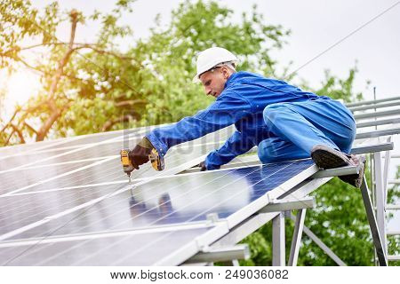 Young Construction Worker Connects Photo Voltaic Panel To Solar System Using Screwdriver On Bright S